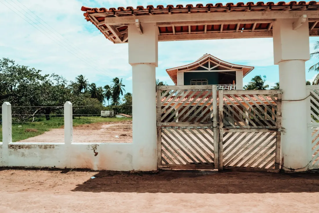 Portão de entrada de um imóvel, com a casa ao fundo